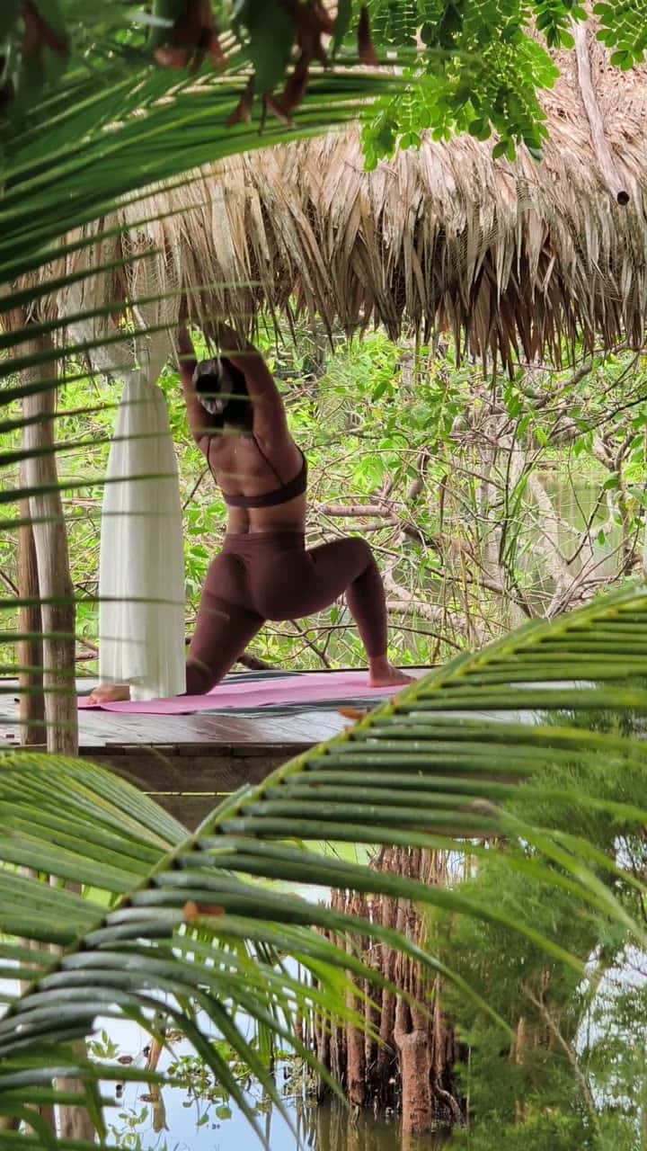Woman practising yoga in a thatched garden sala over a tranquil pond in Koh Samui