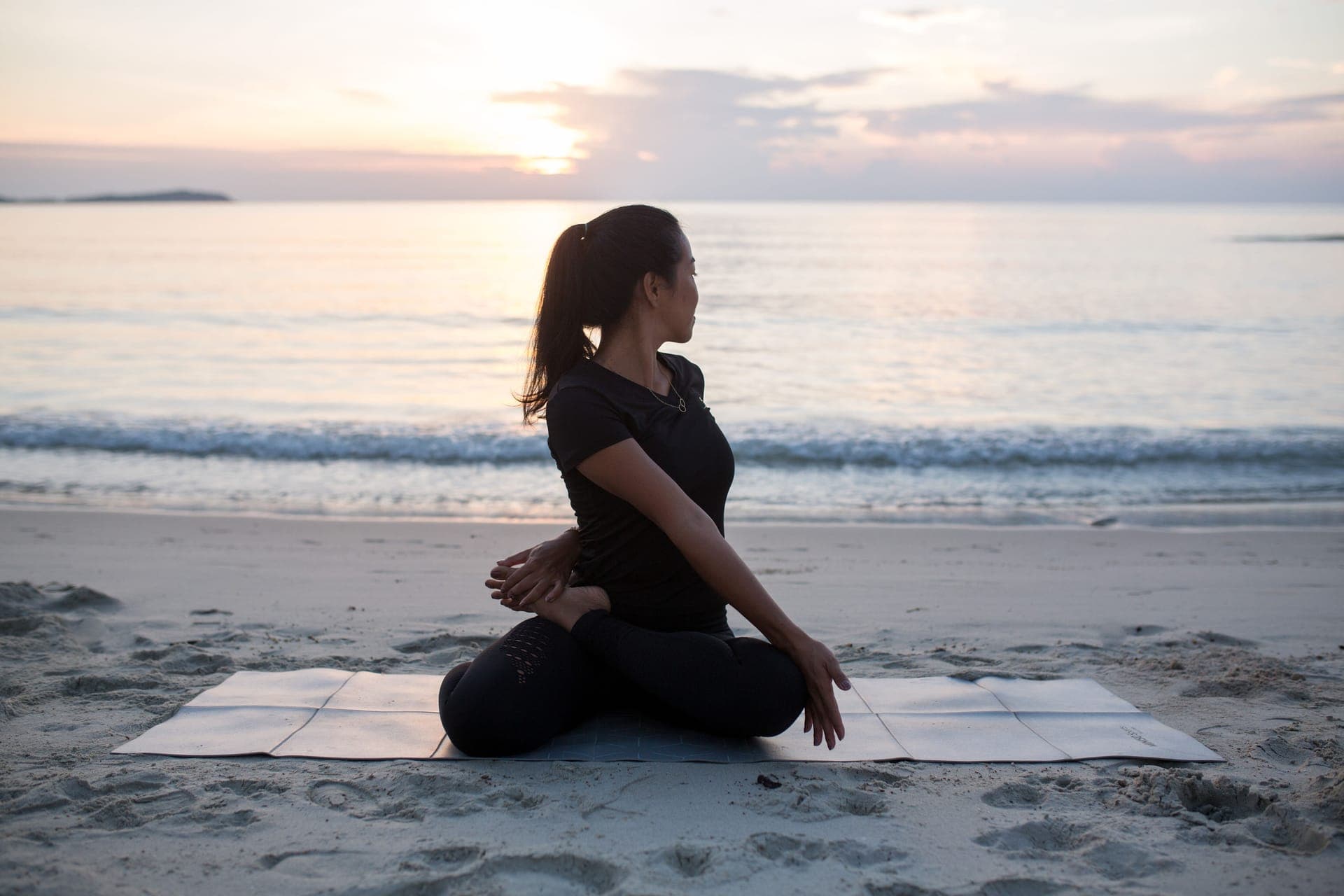 A yoga teacher practising on the sand at sunset on a Koh Samui beach